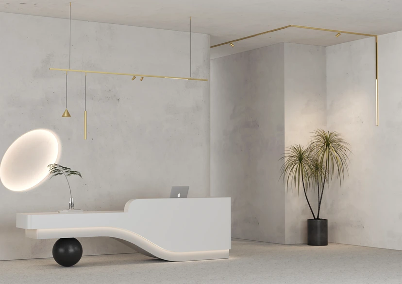 Reception lounge in raw concrete with a brass magnetic track, spot lights, slim pendants and a softly glowing disc