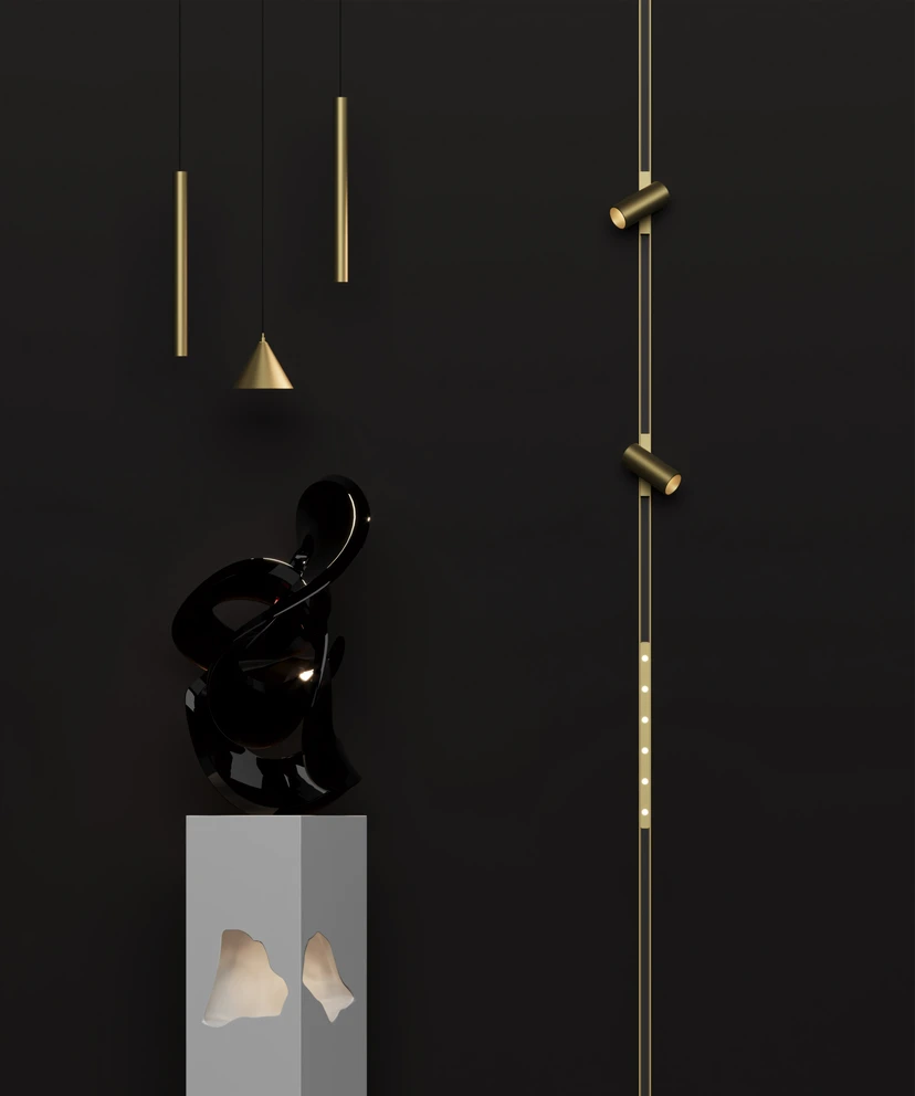 Slim brass pendants and a vertical brass track with spots against a black wall