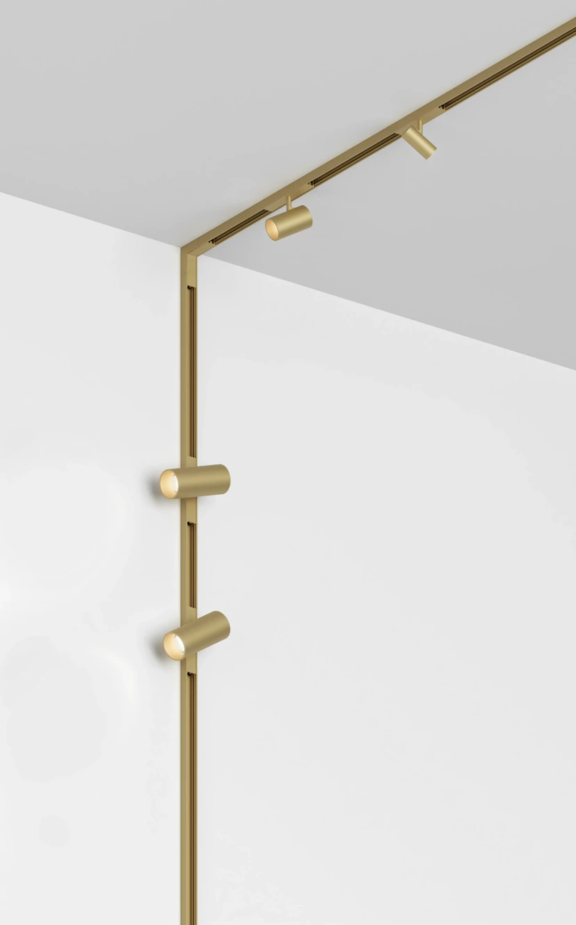 Brass magnetic track turning a wall-to-ceiling corner, with adjustable spots on both the wall and the ceiling