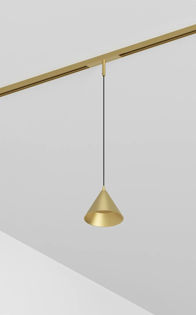A brass cone pendant hanging on a thin cable from a brass magnetic track in a white corner