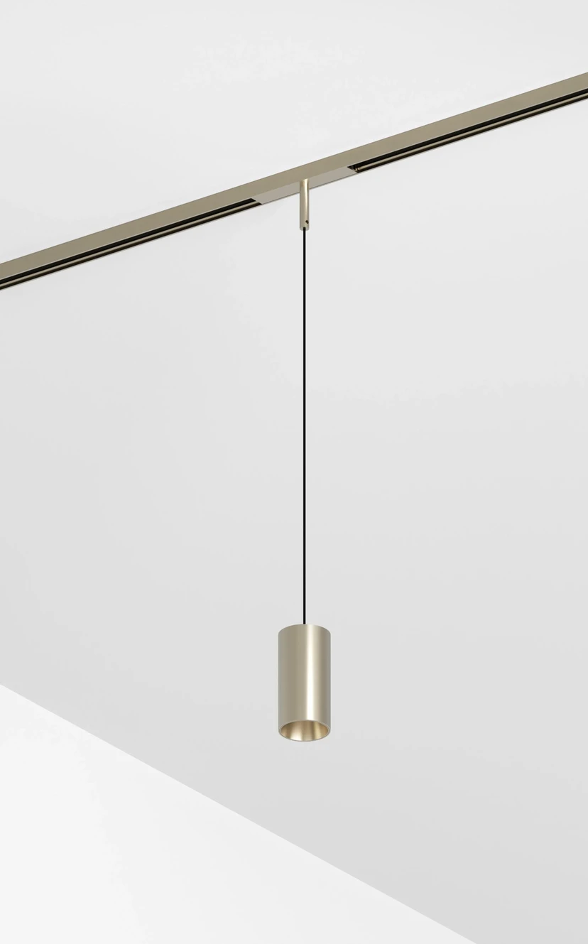 A nickel cylinder pendant hanging on a thin cable from a nickel magnetic track in a white corner